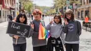 Quatre élèves posent devant la caméra, et tiennent un drapeau LGBTQ et une pancarte sur laquelle il est écrit "Pareil pas pareil". 