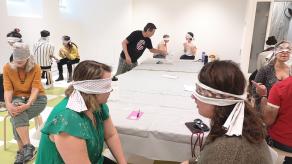 Atelier en intérieur, les participant·e·s discutent, les yeux bandés. Crédit : Sandrine Côté