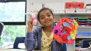 Une élève tient d'une main sa création textile, et de l'autre une petite pochette en tissu. Crédit @ Valentina Plata.