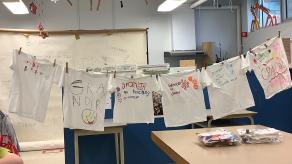 6 chandails décorés sont accrochés sur un fil au milieu d'un local scolaire. Crédit photo @ Yves Amyot.