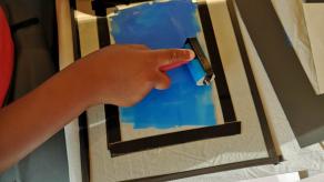 Un·e participant·e encre une surface transparente au rouleau. Crédit @ Sandrine Côté.