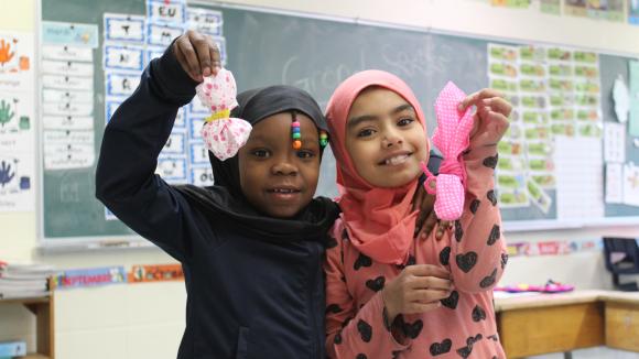 2 élèves souriantes montrent leur créations textiles